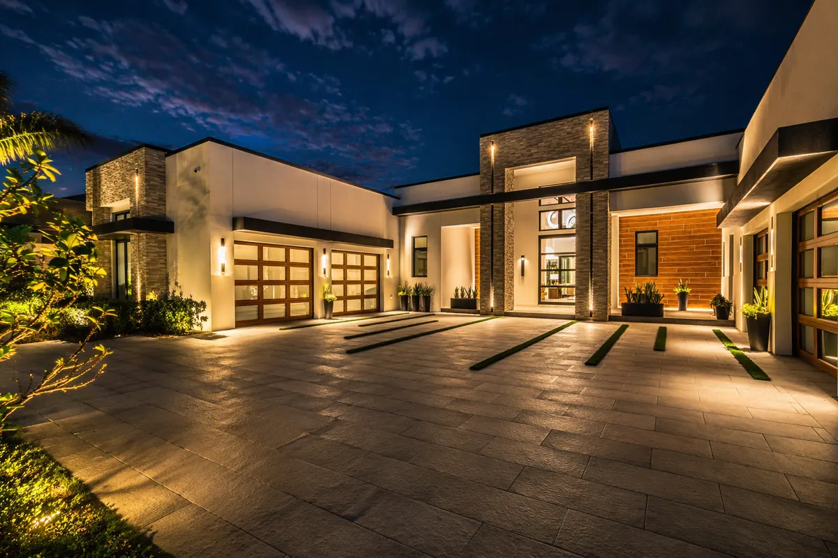 Modern home courtyard at night with linear recessed lighting across the hardscape