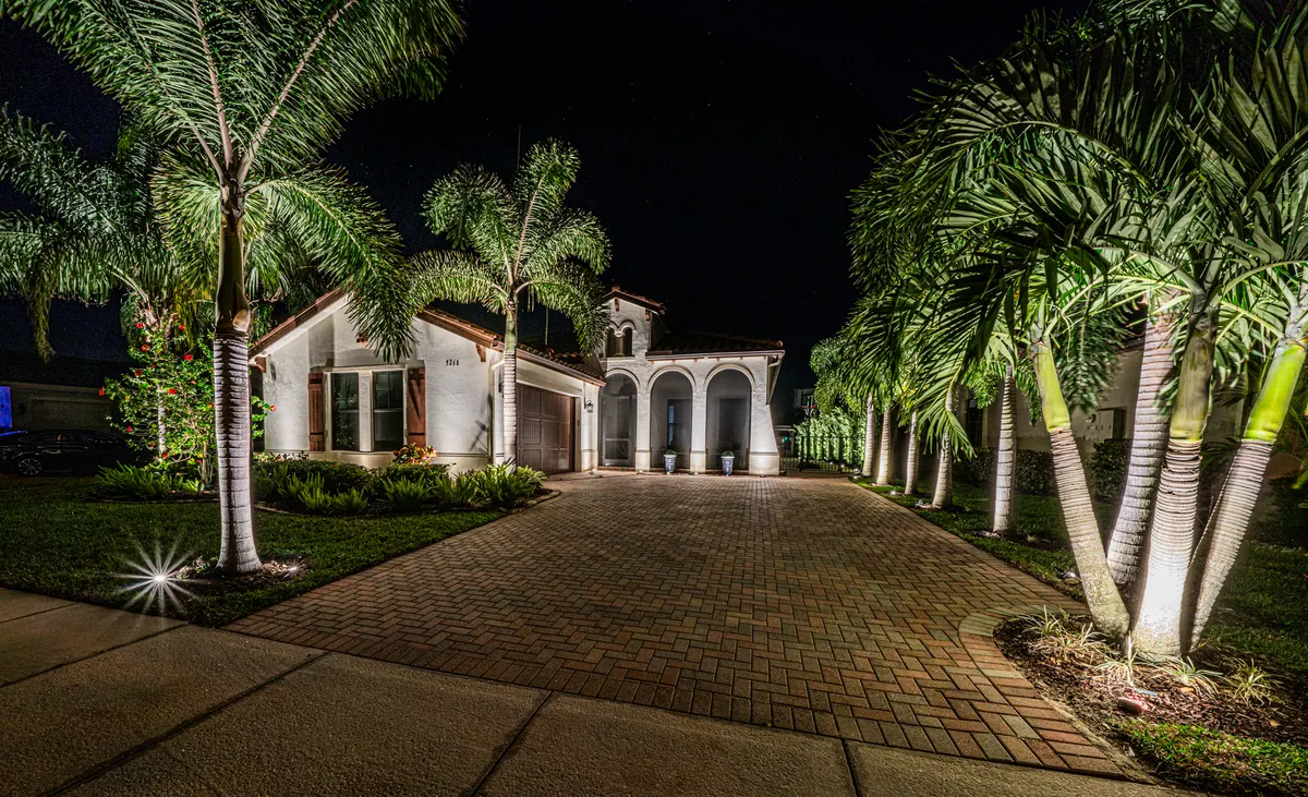 Naples home with a fully restored landscape lighting system glowing at night